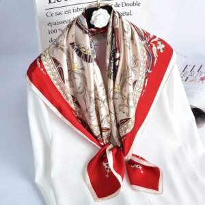 Photo d'un foulard en soie élégant à motifs, beige et rouge, noué autour d'une chemise blanche.