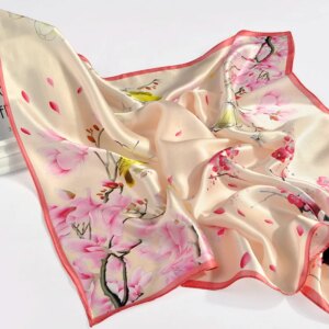 Photo d'un foulard en soie carré rose et beige avec des fleurs et des papillons.