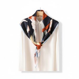 Foulard carré en soie véritable bleu et rouge sur un chemisier blanc et sur fond blanc
