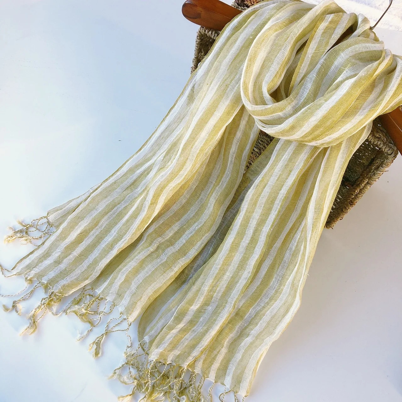 écharpe en lin à rayures jaunes avec des franges, enroulée sur un cintre