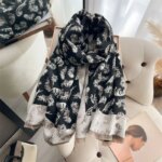 écharpe noire et blanche imprimée de plumes enroulée et déposée sur une chaise devant un miroir