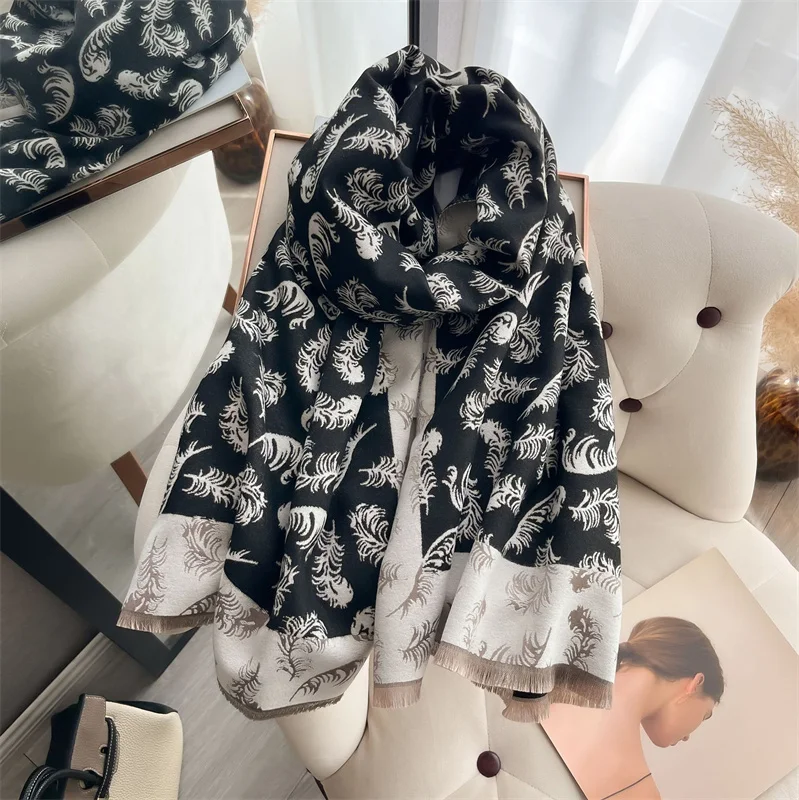 écharpe noire et blanche imprimée de plumes enroulée et déposée sur une chaise devant un miroir
