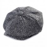 Une casquette béret gavroche enfant look adulte grise en tissu, avec une petite visière, posée sur un fond blanc.